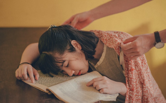 žena spiaca nad knihou